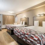 Hotel room with two queen beds, neutral decor, and wood flooring.