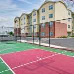 Outdoor basketball court with green and red surfacing in front of a modern apartment building.