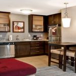 Kitchenette area with dark wood cabinets, stainless steel appliances, and a small dining bar.