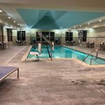 Indoor swimming pool area with lounge chairs and a bright, tiled ceiling.