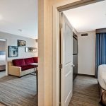 Hotel room interior showing a living area, bedroom, and bathroom entrance.
