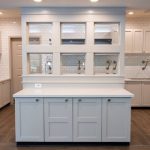 Modern kitchen island with white cabinetry, featuring a tiled backsplash and stainless steel fixtures.