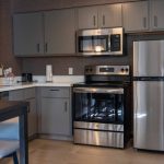 Modern kitchen with stainless steel appliances, dark cabinetry, and light countertops.