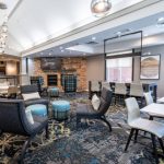 Lobby seating area with modern furniture, fireplace, and large windows.