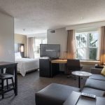Modern studio apartment with living area, workspace, and bedroom visible.