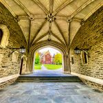 Stone vaulted passageway leading to a historic brick building courtyard.
