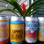 Canned beverages with tropical and summer themes displayed near a vibrant green plant.
