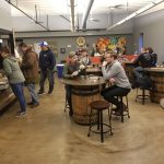 Group of men socializing and drinking in a rustic, industrial-style bar setting.