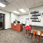 Office reception area with a desk, computers, and large black silhouette art on the wall.