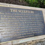 Bronze plaque detailing the sculpture honoring 9/11 and the World Trade Center.