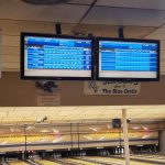 Scoreboard above a bowling alley showing game stats and lane information.