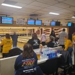 Bowling alley interior with lanes, scoring monitors, and people playing or watching.