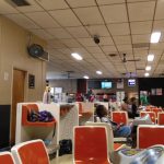 Indoor arcade or entertainment center with games, people playing, and overhead lighting.