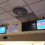 Indoor sports arena with scoreboard displaying game stats and overhead lighting.