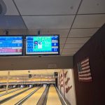 Bowling alley view with digital scoring screens and lanes stretching into the distance.