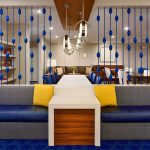 Modern lobby seating area with blue accents, high ceilings, and contemporary lighting fixtures.