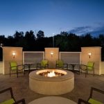 Outdoor patio with fire pit, lounge chairs, and modern architecture at dusk.