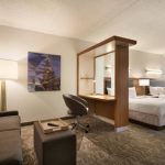 Modern hotel room with sofa, artwork, and view into sleeping area.