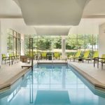 Indoor pool area with large windows overlooking a green outdoor landscape.