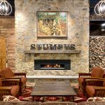 Stone fireplace with "STUMPYS" sign, rustic living room seating area.