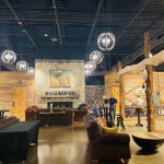 Rustic industrial interior with exposed beams, high ceilings, and hanging globe lights.
