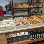 Bakery display case filled with fresh bread, pastries, and packaged coffee beans.