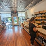 Interior view of a rustic hardware and food store with wooden floors and display counters.