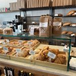 Bakery display case filled with fresh croissants and pastries, stocked shelves in background.