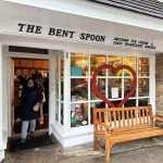 Exterior of The Bent Spoon ice cream and bakery shop with a wooden bench.