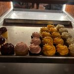 Assortment of small, colorful cupcakes displayed in a metal serving tray.