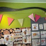 Green wall display featuring a large black spoon, colorful triangles, and food menu boards.