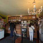 Interior view of a cozy cafe with wooden counters, warm lighting, and patrons seated.