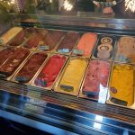 Assortment of colorful gelato flavors displayed in a refrigerated glass case.