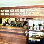 Coffee shop counter with menu board featuring various baked goods and drinks.