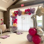 Birthday party setup with a large gold number 1 balloon and purple/pink decorations.