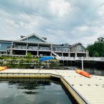 Waterfront house complex with docks, boats, and cloudy sky.