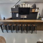 Coffee bar setup with counter, stools, and espresso machine in a modern cafe.