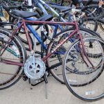 Vintage bicycles parked outdoors, featuring a prominent maroon and blue frame in the foreground.