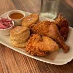 Fried chicken, biscuits, and coleslaw served on a white platter with dipping sauce.