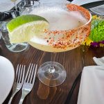 Spicy margarita cocktail garnished with lime on a dark wooden table.