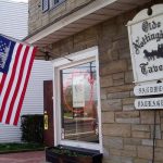 American flag hangs near a stone building with "Olde Nottingham Tavern" sign.