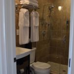 Modern bathroom with white sink, toilet, and glass-enclosed shower.