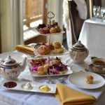 Elegant afternoon tea spread with pastries, tiered stand, and teapots on a white tablecloth.