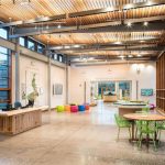 Modern, bright open-plan office space with wood ceiling and large windows.
