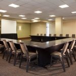 Conference room setup with tables, chairs, and a projection screen for meetings.