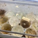 Various containers filled with different colored and textured doughs or batters in a refrigerator.