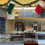 Bakery display case featuring pastries, with menu boards advertising coffee and treats.