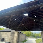 Large wooden pavilion structure with exposed beams and roof, supported by stone pillars.