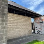 Modern building exterior with textured brick walls and a patterned entrance area under an overhang.