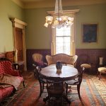 Elegant dining room with chandelier, wooden paneling, and patterned rug.